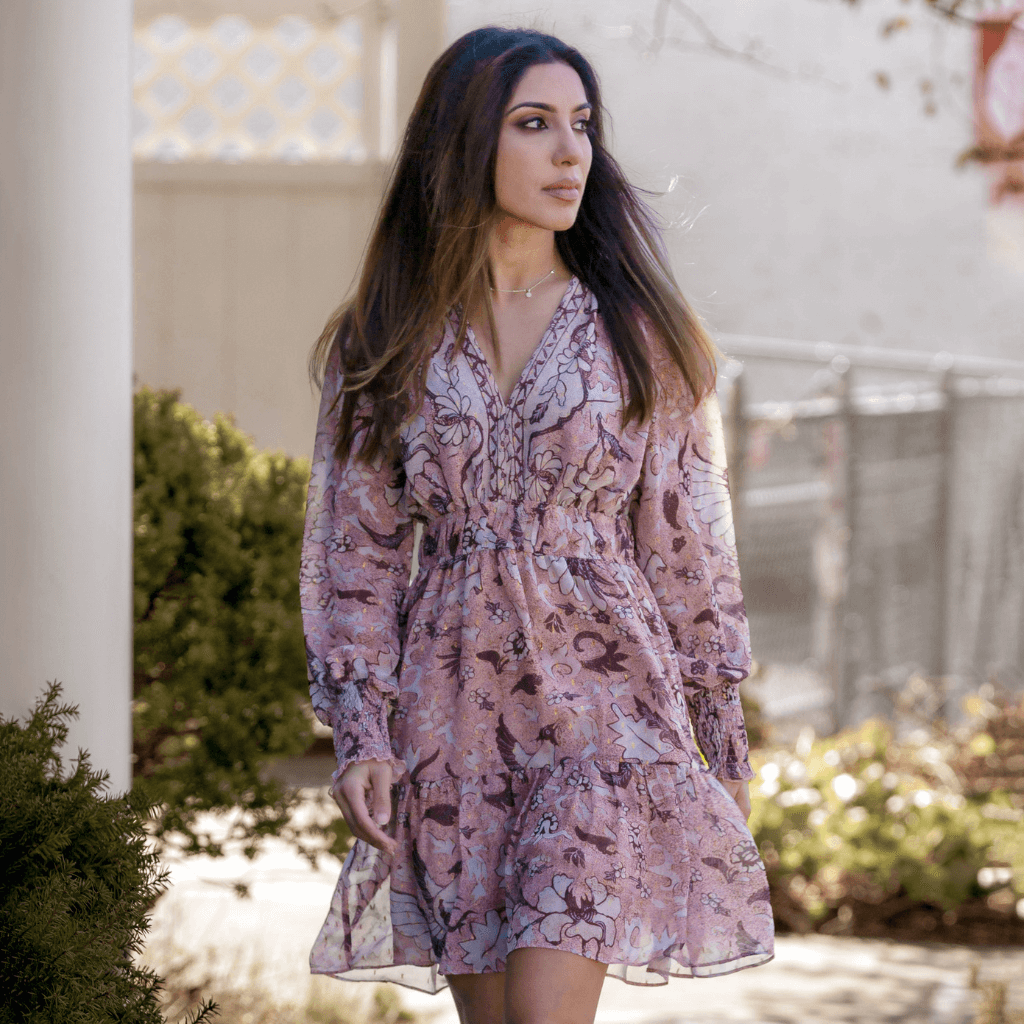 Femme portant une robe à fleurs roses, déambule dans un jardin, style élégant et printanier.