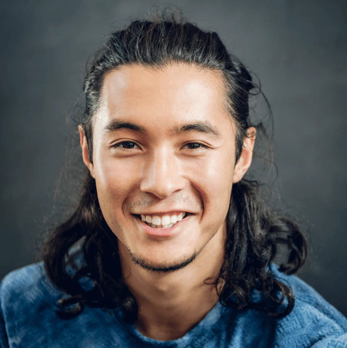 Homme souriant avec des cheveux longs, représentant la vitalité et le soin de la peau, id&eacute;al pour la routine beauté.