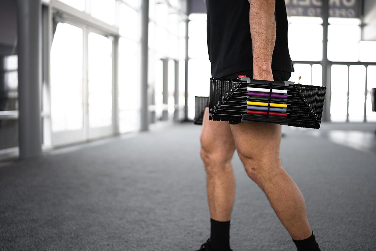 Homme utilisant les Autera FlexWeights™ dans un gymnase, entraînement avec haltères réglables innovants.