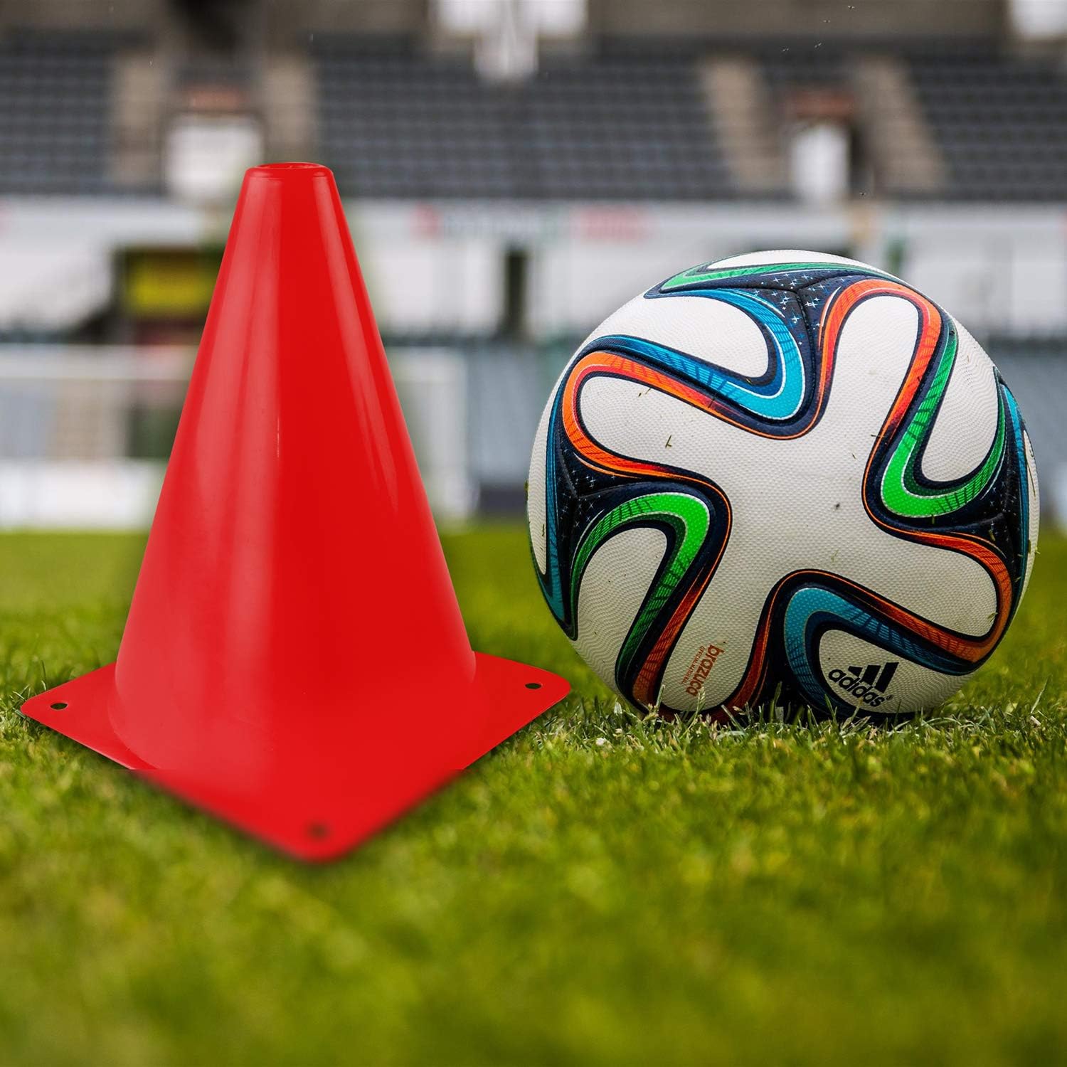 Autera CoreDisc™ training accessory with red cone and soccer ball on grassy field.